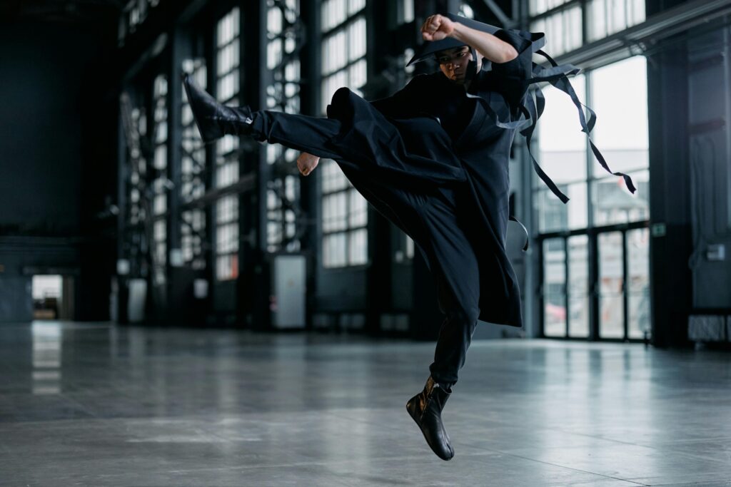 pexels photo 7777279 7777279 Martial artist in black attire executes powerful jump kick in spacious industrial setting.